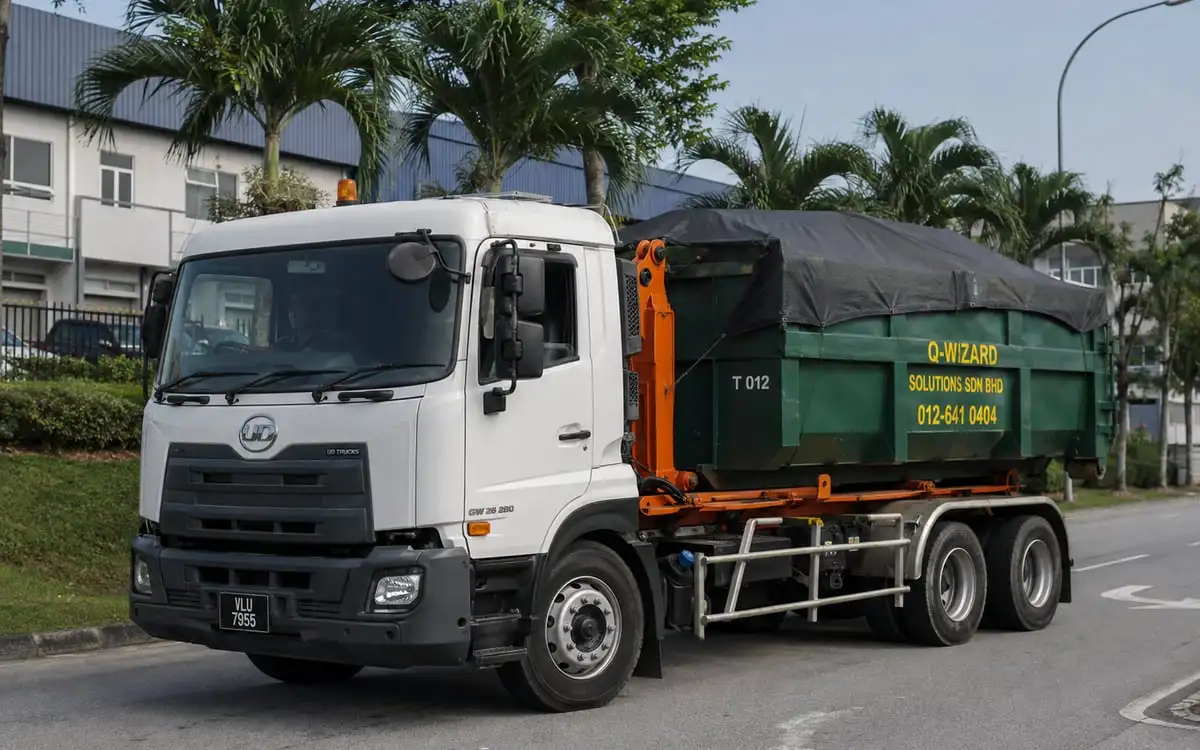Illustration of a loaded hook-lift truck with a covered green bin on a Malaysian industrial road.